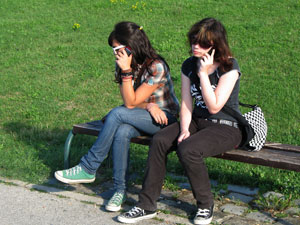 Young women talking on cell phones in park